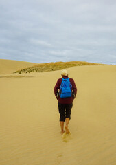 A woman walking on the Giant Sand Dunes, Cape Reinga, New Zealand.