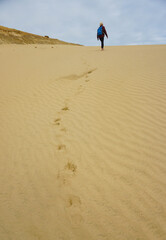 A woman walking on the Giant Sand Dunes, Cape Reinga, New Zealand.