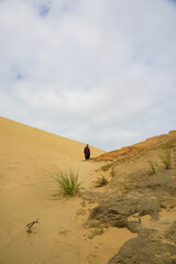 A woman walking on the Giant Sand Dunes, Cape Reinga, New Zealand.