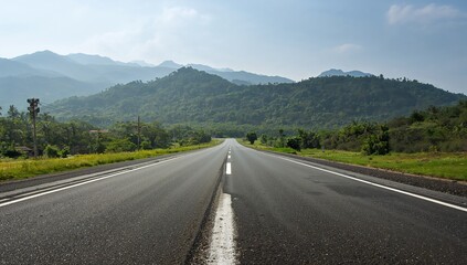 Fototapeta premium A long straight road through a mountainous landscape with trees