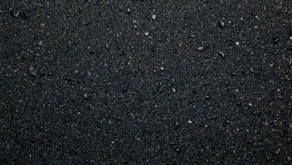 Dark gray asphalt surface with small stones and pebbles texture