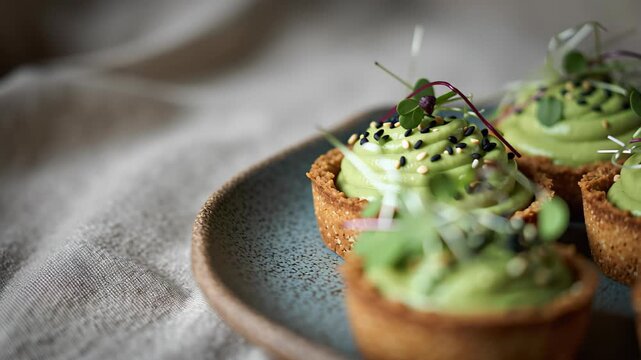Avocado-lime tartlets with microgreens and sesame seeds styled in cinematic editorial food photography