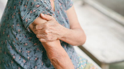 Senior woman suffering from arm pain, holding her shoulder due to muscle ache or arthritis. Concept...