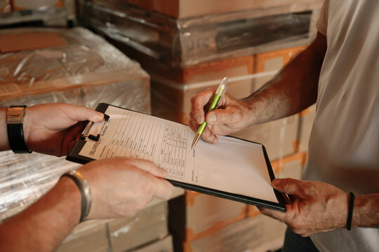 Warehouse worker signing delivery documents held by a colleague