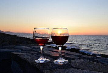 Zwei Weingläser mit Rotwein mit dem Sonnenuntergang im Hintergrund auf Kreta, Griechenland