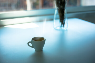 Espresso hot cup of coffee put on table near the window