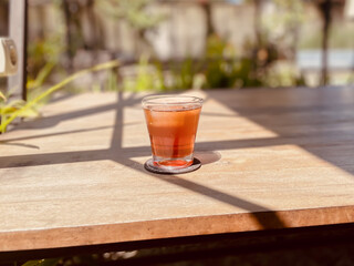 Refreshing Glass of Iced Tea on a Sunlit Wooden Table Outdoors.