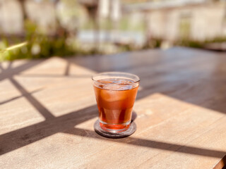 Refreshing Iced Drink on a Wooden Table with Sunlit Shadows, Outdoors.