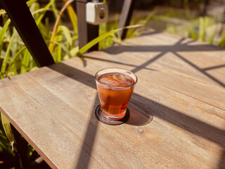Refreshing Iced Tea in a Glass on a Sunny Wooden Table Outdoors