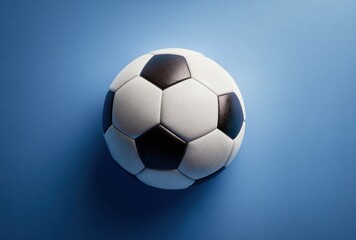 Naklejka premium Close-up of a classic black and white soccer ball resting on a smooth blue with soft lighting and subtle shadows