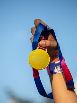 Hand holding medal on sky background, The winner and successful concept