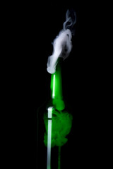 Green glass bottle with strange swirling smoke inside and out creating unique shapes and patterns