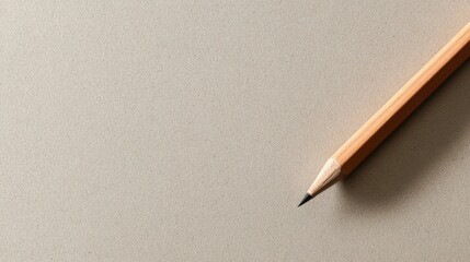 Close-up of a wooden pencil with a sharpened tip resting on a smooth, beige with subtle shadows