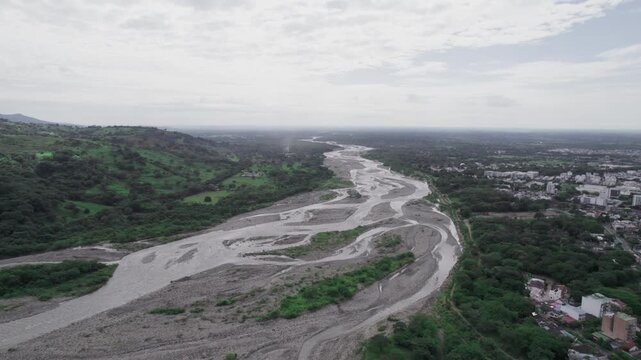 Aerial zoom in of Cravo Sur river near Yopal, Colombia, showing the wide riverbed and surrounding green landscape.