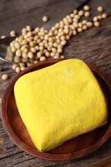 Soybeans and yellow tofu on wood background