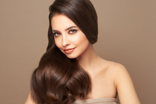 Brunette girl with perfect makeup. Smiling beautiful model woman with long curly hairstyle. Care and beauty hair products