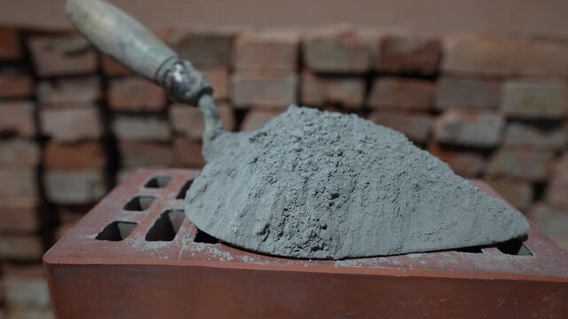 Dry cement or mortar. Cement powder and trowel on red brick at construction site, close up, rotates