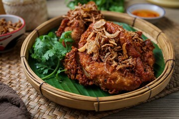 Fried chicken topped fried shallots with sticky rice and thai sauce in banana leaf on wooden background, thai called kai tod hat yai
