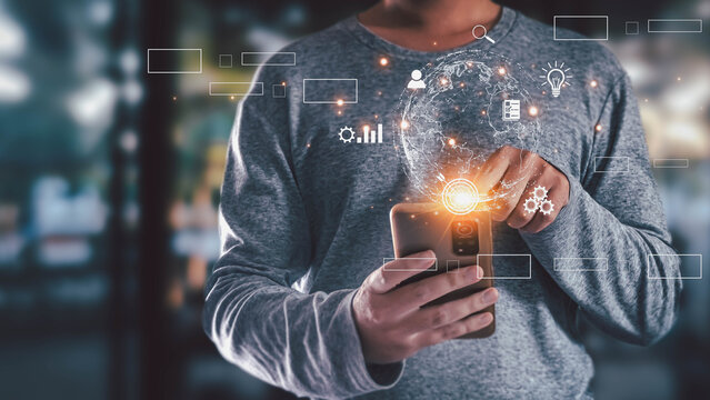 Man using smartphone with holographic globe and business icons. Concept of global technology, digital transformation, network connection, and innovative ideas.