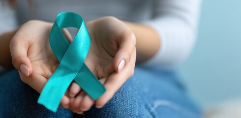 Close up of woman holding a teal ribbon, symbolizing support for ovarian cancer awareness and gynecologic cancer research