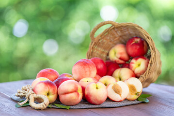 Fresh peach drop from bamboo basket on blurred greenery background, Peach fruit in Bamboo basket on wooden table in garden.