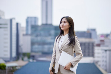 Fototapeta premium スーツを着てラップトップを抱えた日本人女性