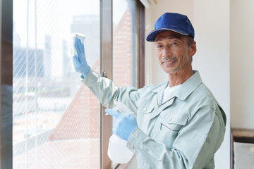 窓拭きをする清掃業者のシニア男性 © polkadot