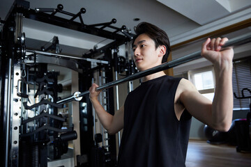 フィットネスジムで筋力トレーニングを行うスポーツウェアを着た若い日本人男性