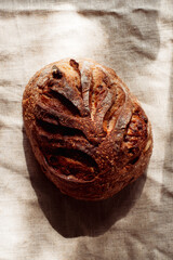 cranberry walnut sourdough bread on natural linen texture background.