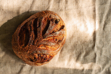 cranberry walnut sourdough bread on natural linen texture background.