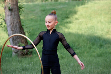 Young gymnast girl in a black outfit skillfully practicing her rhythmic gymnastics routine outdoors...