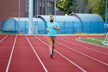 Person actively running on a bright red athletic track outdoors, promoting health and fitness. Man...