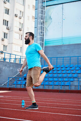 Active male practicing leg stretch exercise on a track at a stadium. Fitness and activity portrayed...