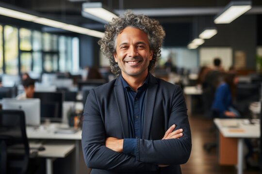 A man with curly hair stands confidently in a contemporary office filled with coworkers engaged in work. Sunlight pours through large windows, highlighting a productive atmosphere - Powered by Adobe