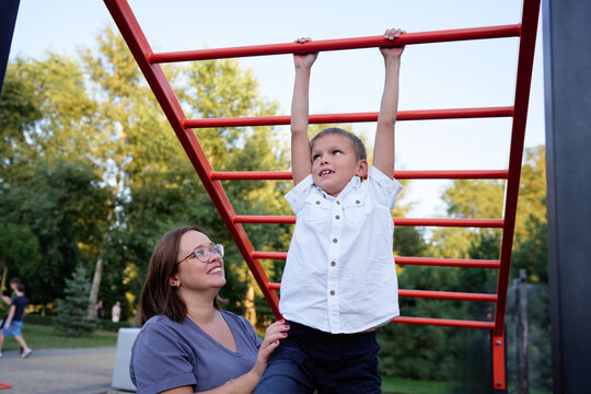 Mother Helping Her Son Learn on Playground Monkey Bars