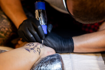 Tattoo artist carefully working on a client’s leg design under focused light. Concept of precision, artistry, creativity, and modern body art in a professional tattoo studio