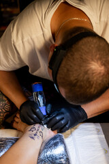 Tattoo artist carefully working on a client’s leg design under focused light. Concept of precision, artistry, creativity, and modern body art in a professional tattoo studio