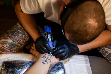 Tattoo artist carefully working on a client’s leg design under focused light. Concept of precision, artistry, creativity, and modern body art in a professional tattoo studio