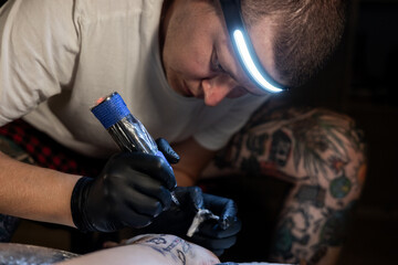 Tattoo artist carefully working on a client’s leg design under focused light. Concept of precision, artistry, creativity, and modern body art in a professional tattoo studio