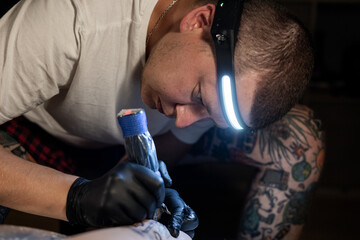 Tattoo artist carefully working on a client’s leg design under focused light. Concept of precision, artistry, creativity, and modern body art in a professional tattoo studio