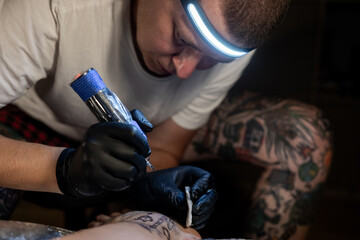 Tattoo artist carefully working on a client’s leg design under focused light. Concept of precision, artistry, creativity, and modern body art in a professional tattoo studio