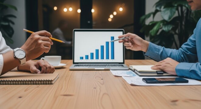 Two business professionals discussing a growth chart on a laptop during a meeting, highlighting financial analysis and successful strategy