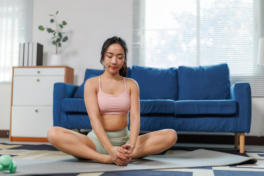 Young asian woman doing bound angle pose on yoga mat at home