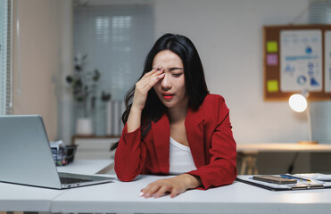 Asian businesswoman feeling tired and stressed while working late in office at night