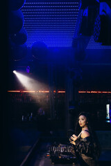 Obraz premium DJ Performing at a Nightclub with Vibrant Lights and Modern Mixing Equipment
