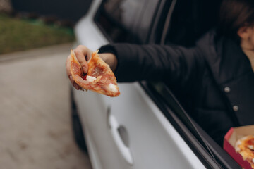 Hand Holding Pizza Slice From Car Window for a Quick Snack on the Go