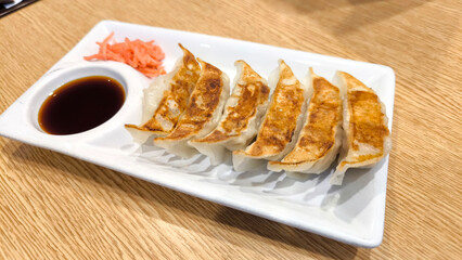 Japanese Gyoza with Dipping Sauce and Pickled Ginger on White Plate
