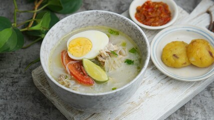 Soto Banjar in a bowl with sambal and potato cake. Selective focus