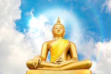 Golden Buddha statue on bright sky background with beautiful shining rays of light, Buddhist faith