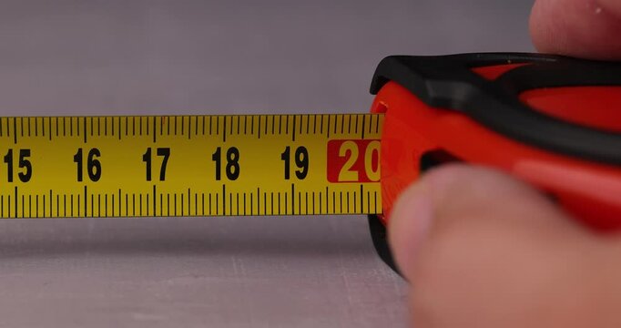 Yellow retractable tape measure opening and closing in slow motion construction tool concept